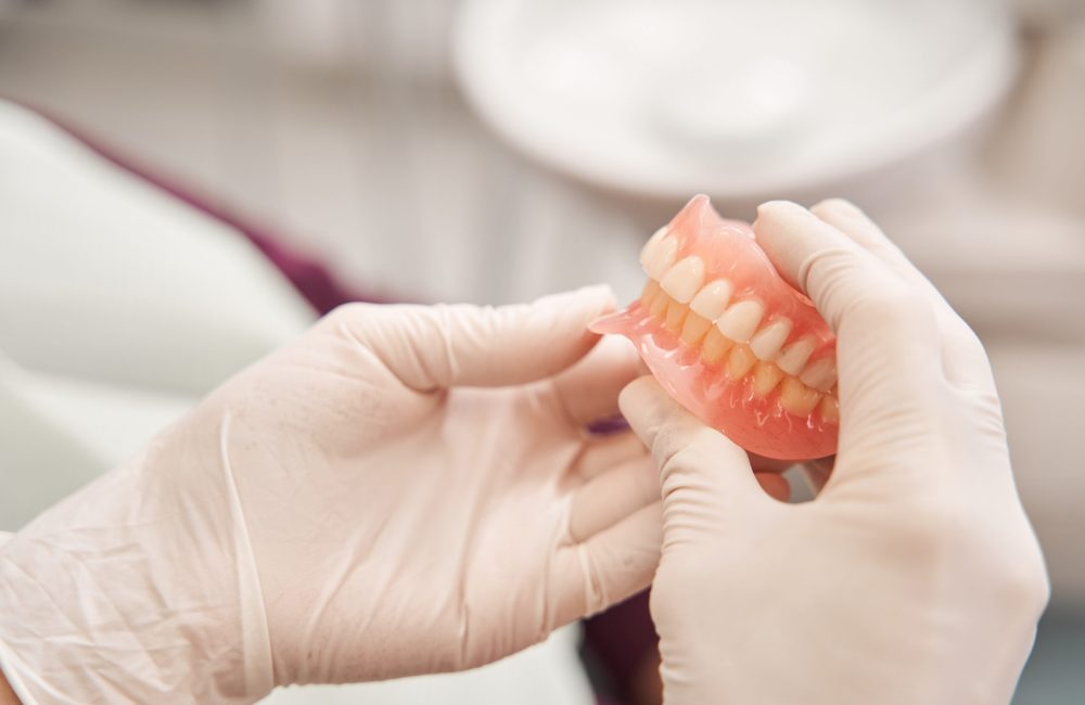 Dentist holding dentures in her hands Dentures provided by Darren Gonzalez DDS in Santa Rosa, CA 95405