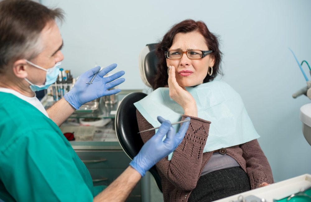 Woman feeling toothache, touching cheek with hand at dental clinic. Senior dentist trying to help. Dental care and health concept Woman in need of emergency dental care in Santa Rosa, CA 95405